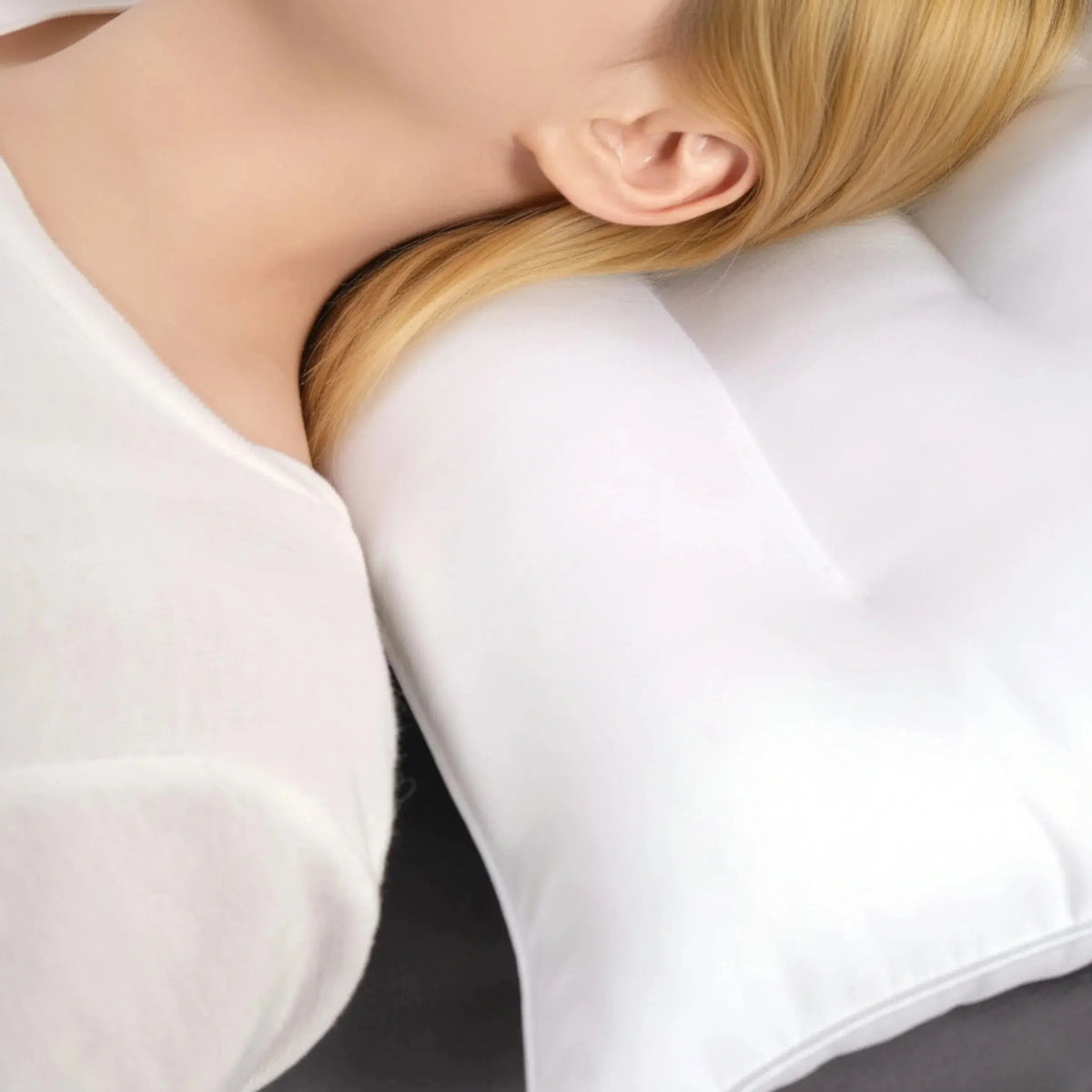 Close-up of a white low loft cotton pillow supporting the neck