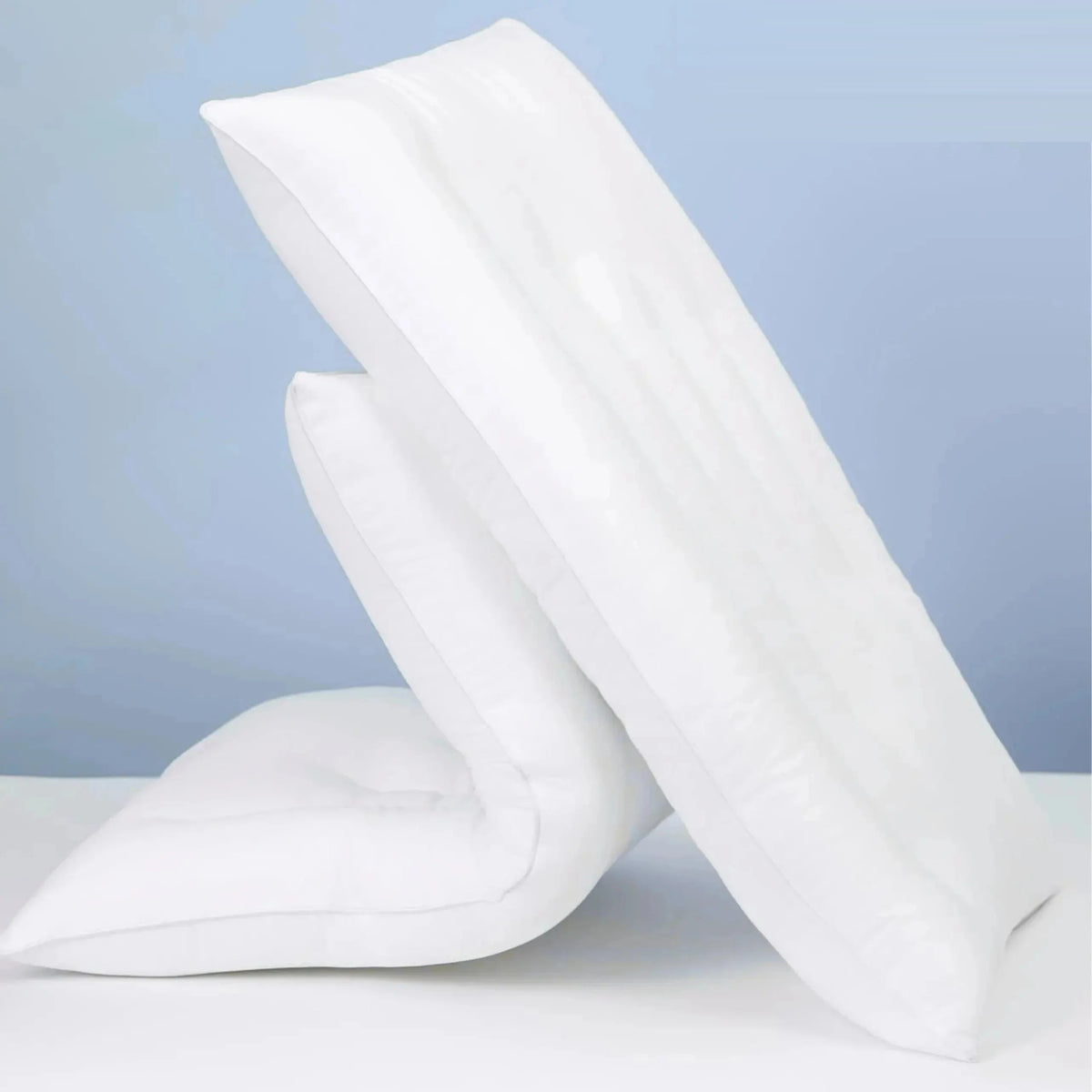 Two white low loft cotton pillows leaning against each other